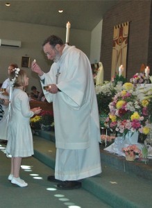 Deacon George Benson distributes the First Eucharist 